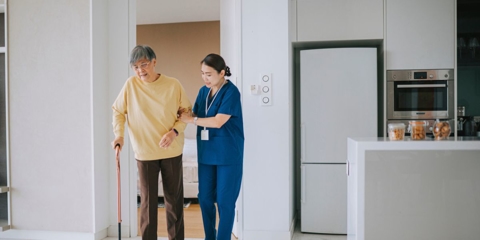 Caregiver assisting elderly man using a cane.