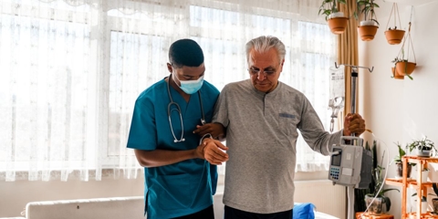 Home care attendant assisting an older man.