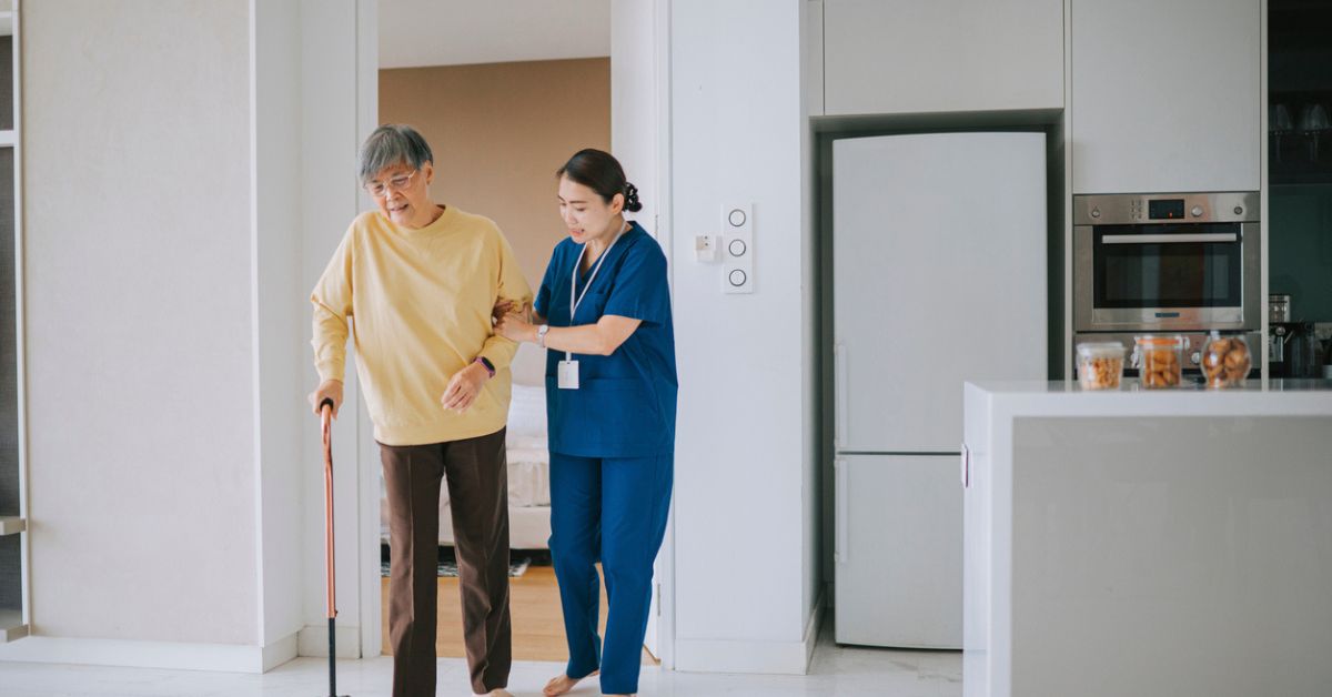 Caregiver assisting elderly man using a cane.