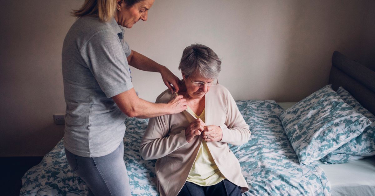 Home care attendant assisting an older woman.