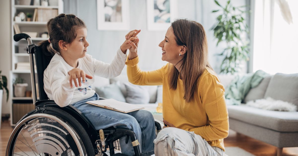 Photo of a child in a wheelchair high-fiving her caregiver.