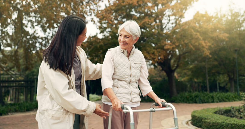 attendant helping senior woman walk